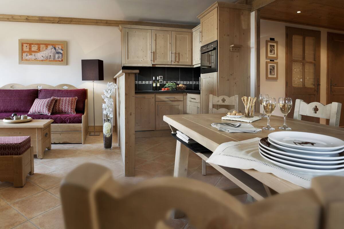 Una sala de estar acogedora con un sofá, una mesa de comedor dispuesta para una comida y una cocina con armarios de madera y estufa.
