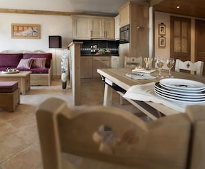 Una sala de estar acogedora con un sofá, una mesa de comedor dispuesta para una comida y una cocina con armarios de madera y estufa.