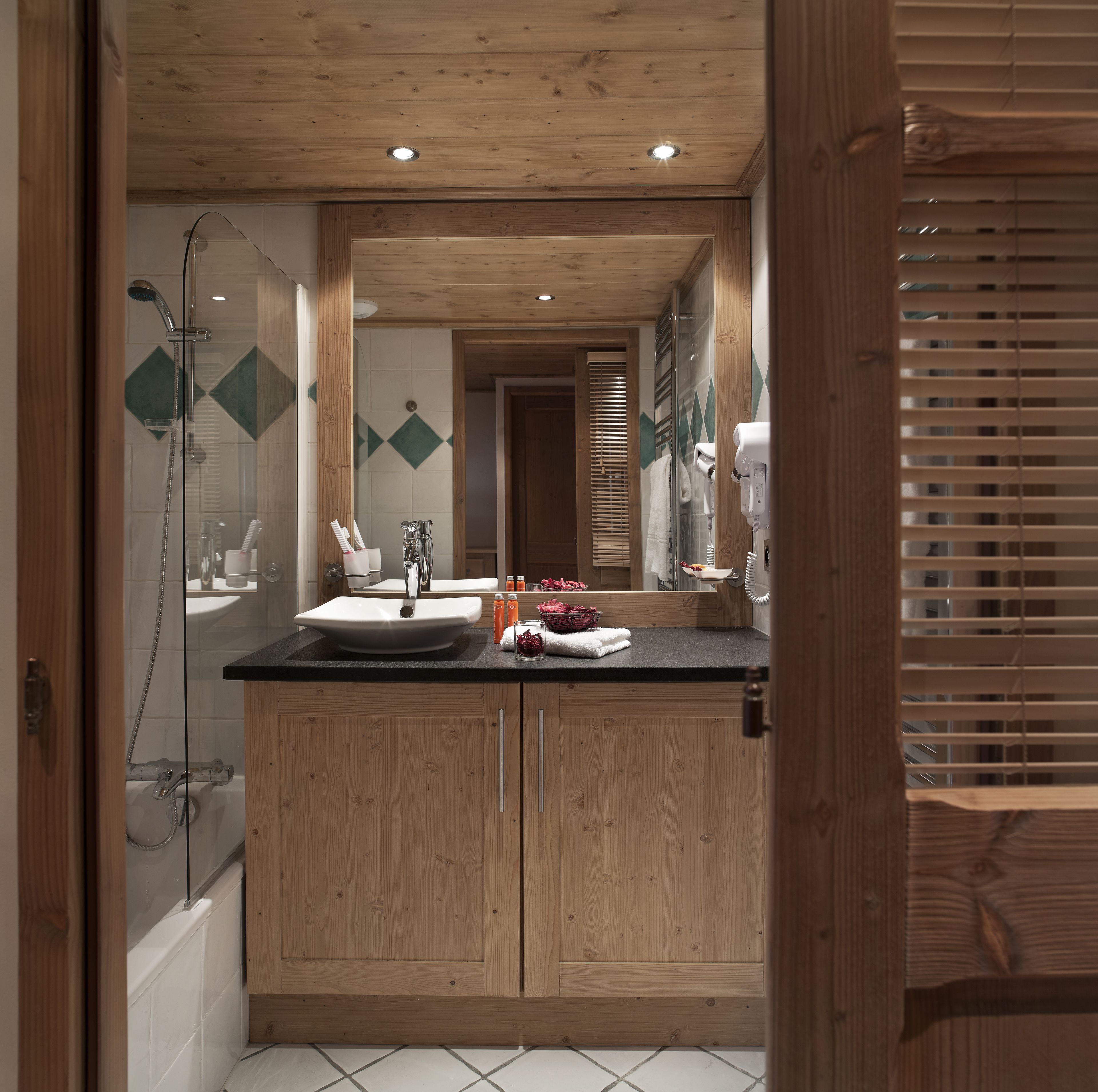 A modern bathroom with wooden cabinetry, a large mirror, and a shower.