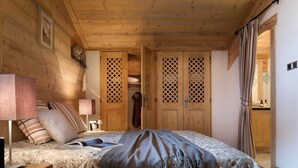 Une pièce en bois avec un lit, une table de chevet, une lampe et une armoire.