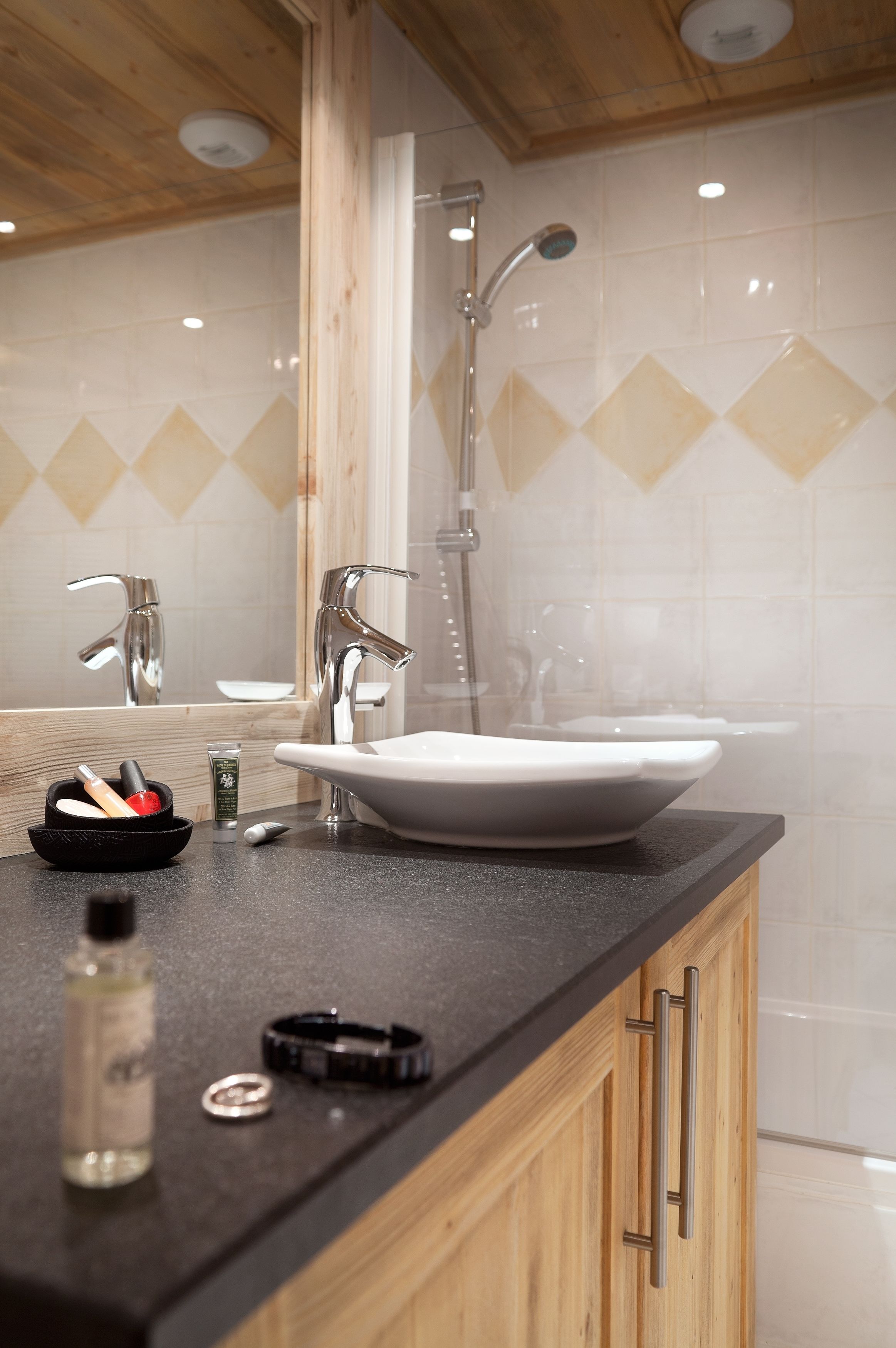 A modern bathroom with a large sink, two faucets, and a showerhead.