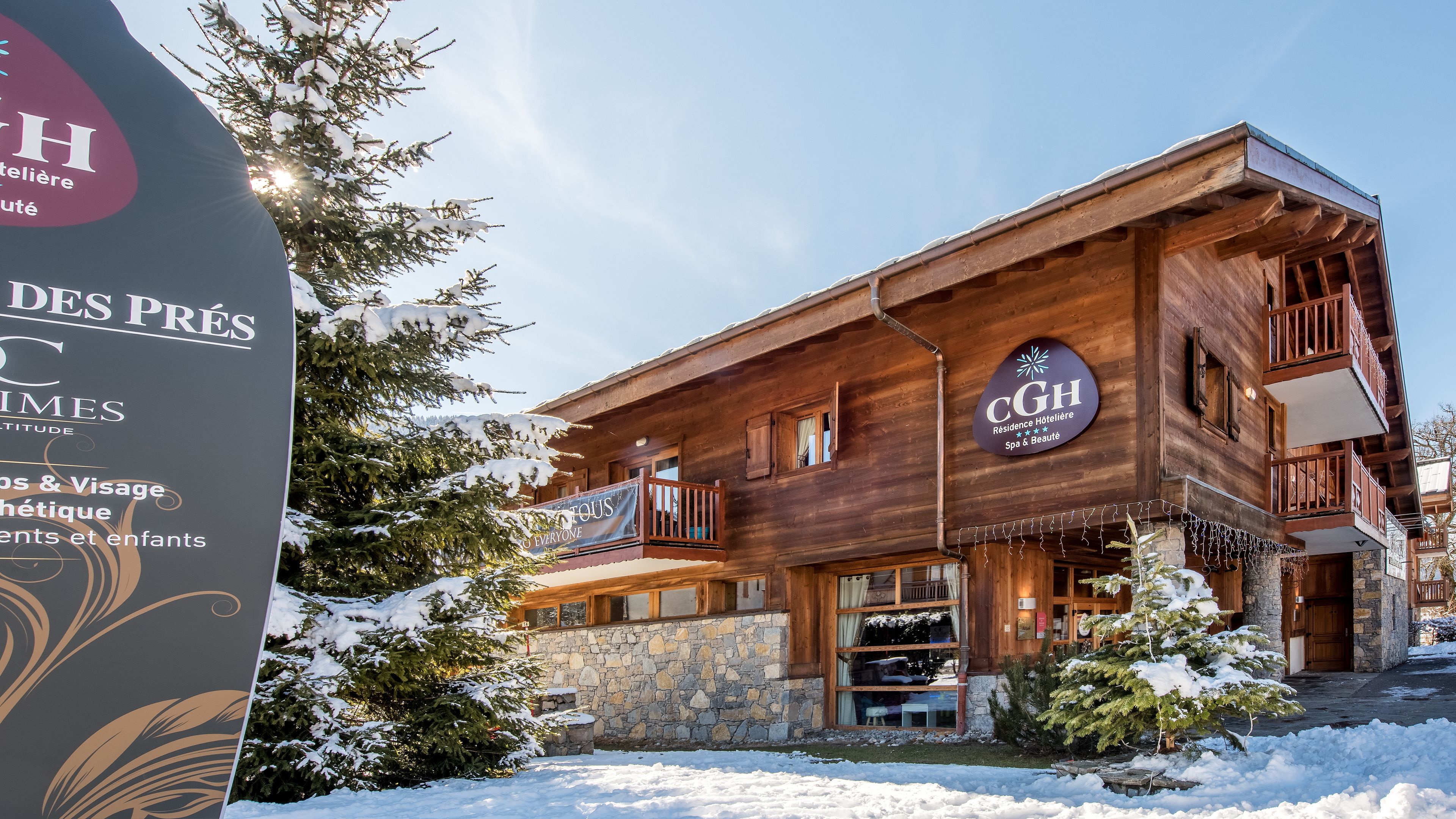 A wooden building with a stone base, balconies, and a sign indicating it is a hotel.