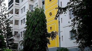 A multi-story residential building with balconies, surrounded by greenery and potted plants. - Perfect Haven Egmore Serviced Apartments (Chennai)