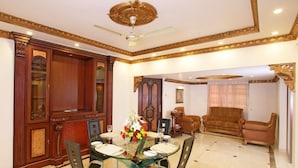 A dining area with a glass table, chairs, and a chandelier. - Perfect Haven Egmore Serviced Apartments (Chennai)