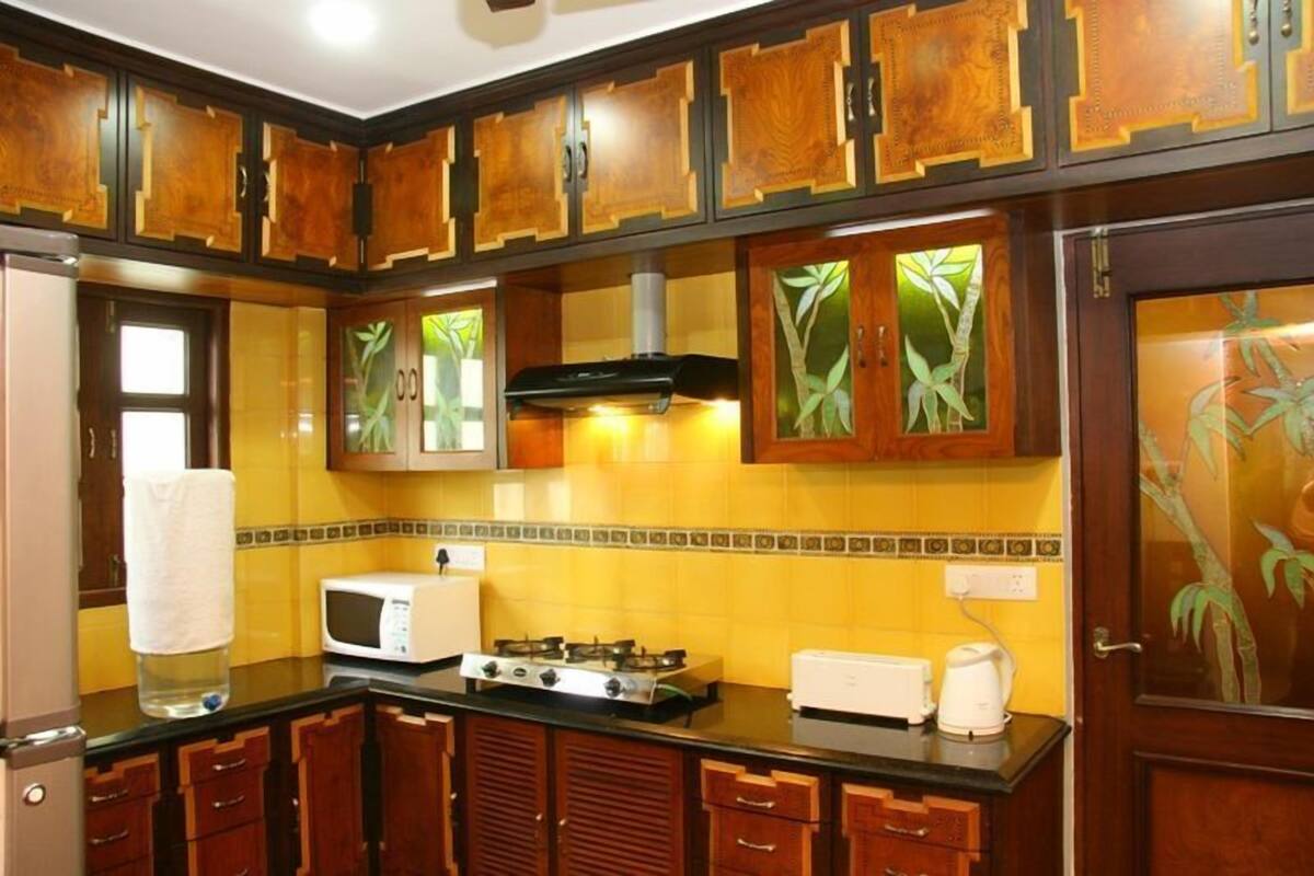 Une cuisine avec des meubles de rangement en bois, un four à micro-ondes, une cuisinière et un grille-pain.