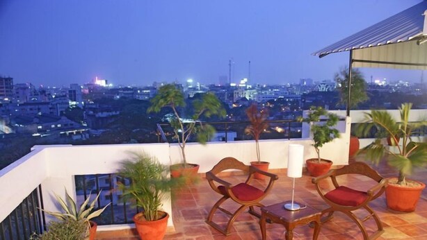 A rooftop terrace with potted plants, wooden chairs, and a table. - Perfect Haven Egmore Serviced Apartments (Chennai)
