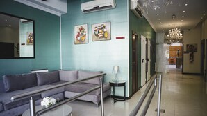 Een moderne lobby met een grijze bank, een glazen salontafel en een kroonluchter.