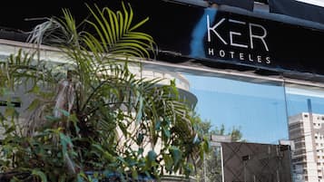 Un letrero de hotel con el nombre "KER HOTELES" y un edificio moderno al fondo.