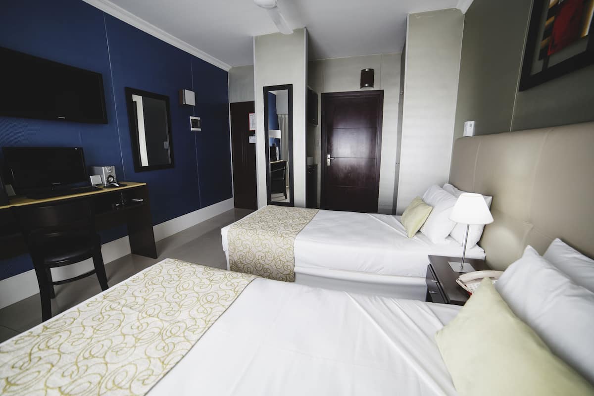 Une chambre d’hôtel avec deux lits, un bureau, une télévision et un miroir.