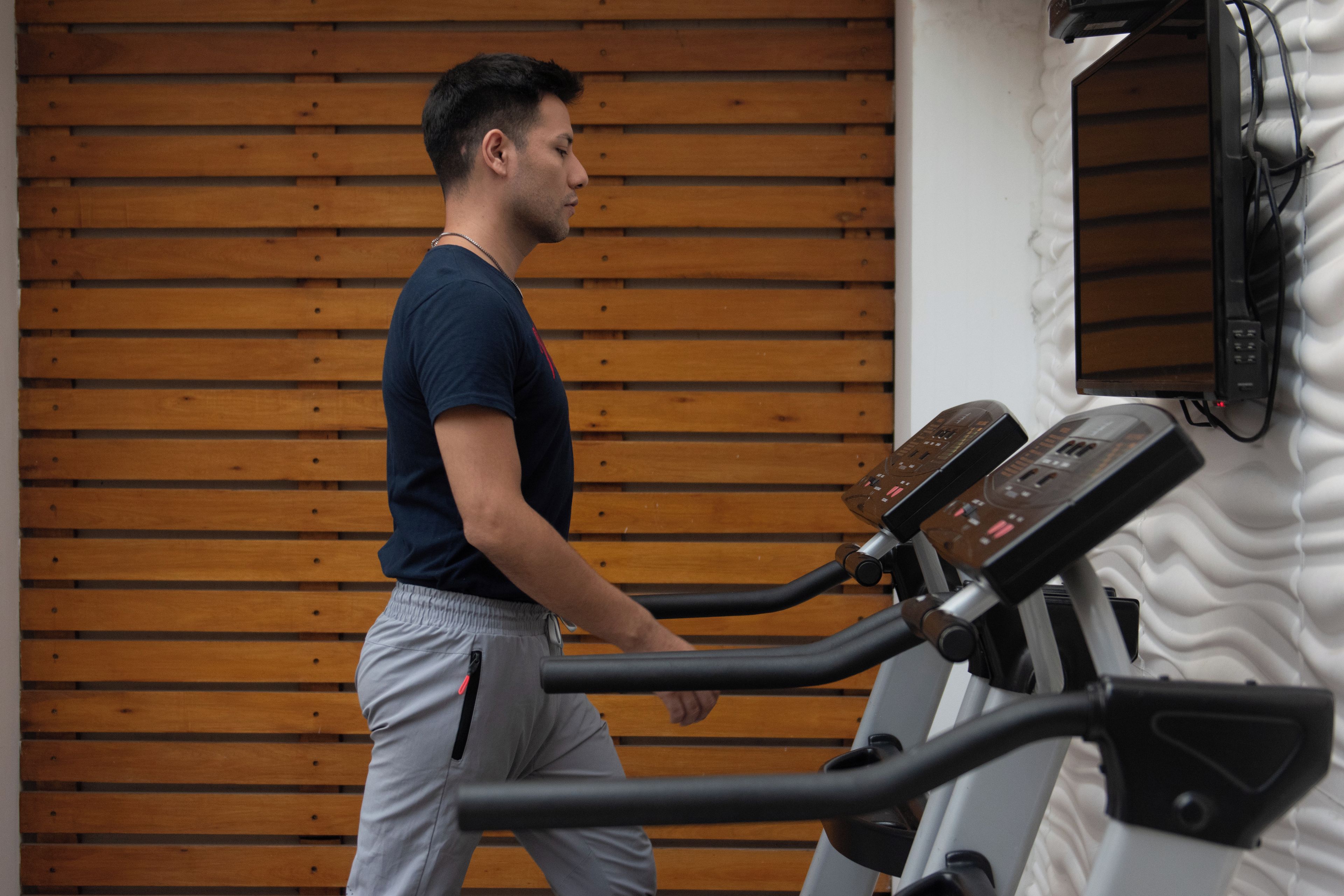Una persona usando una bicicleta estática en una habitación con paneles de madera.