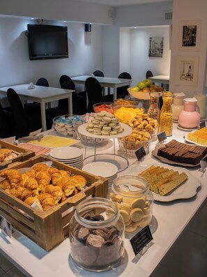A buffet with various food items including pastries, fruits, and desserts.