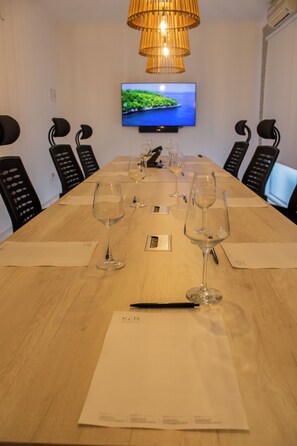 A conference room with a long table, six chairs, and a television mounted on the wall.