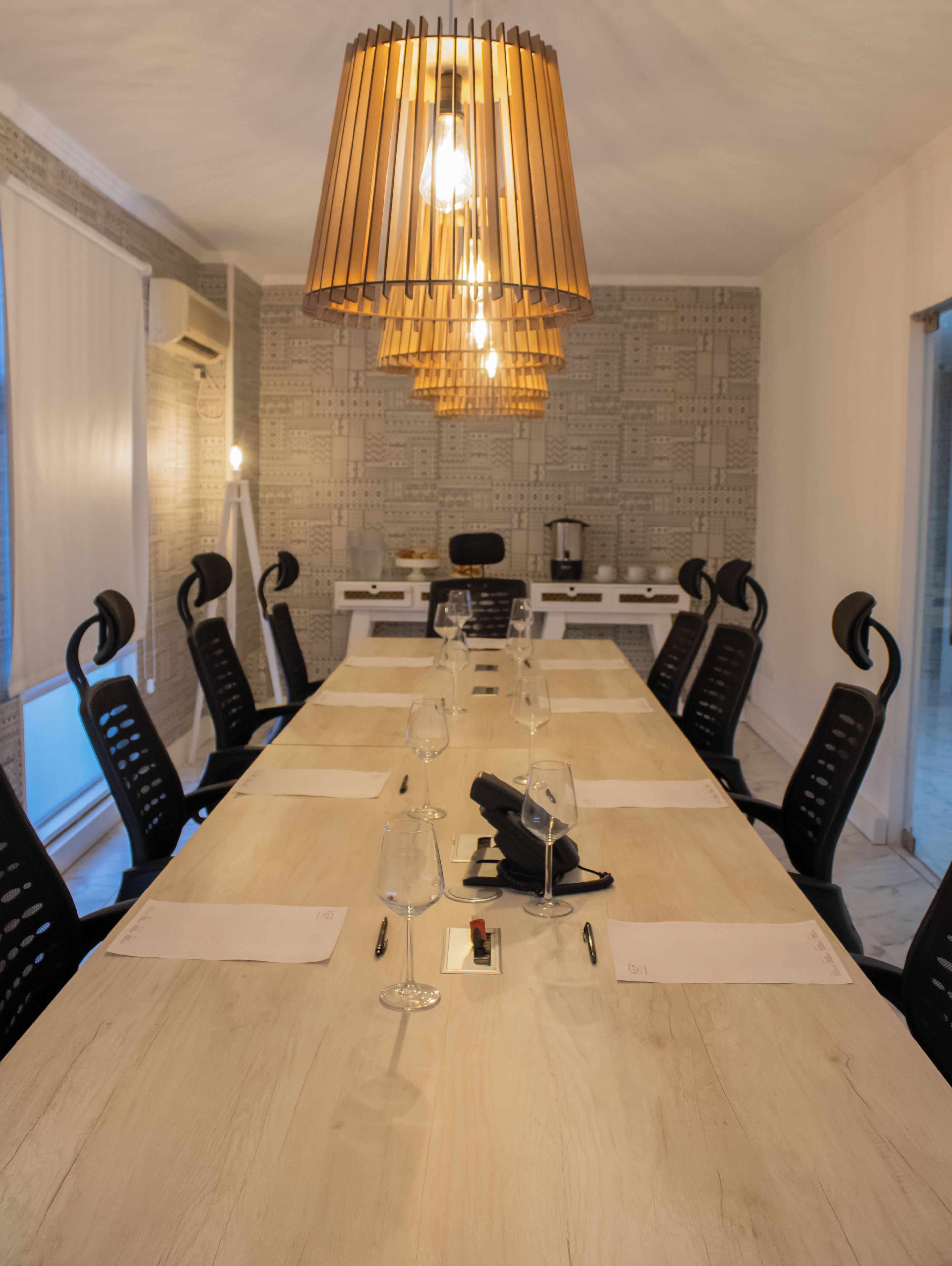 Een vergaderzaal met een lange tafel, stoelen en een hangende lamp.