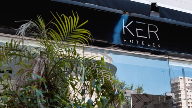 Een hotelschilt met de naam 'KER HOTELES' en een modern gebouw op de achtergrond.