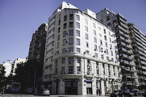 Un edificio de varios pisos con entrada en esquina, ventanas grandes y balcones.