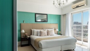 Een moderne hotelkamer met een groot bed, een nachtkastje met lamp, een spiegel en uitzicht op de stad door een groot raam.