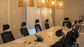 Un salón de conferencias con una larga mesa, sillas negras e iluminación colgante.