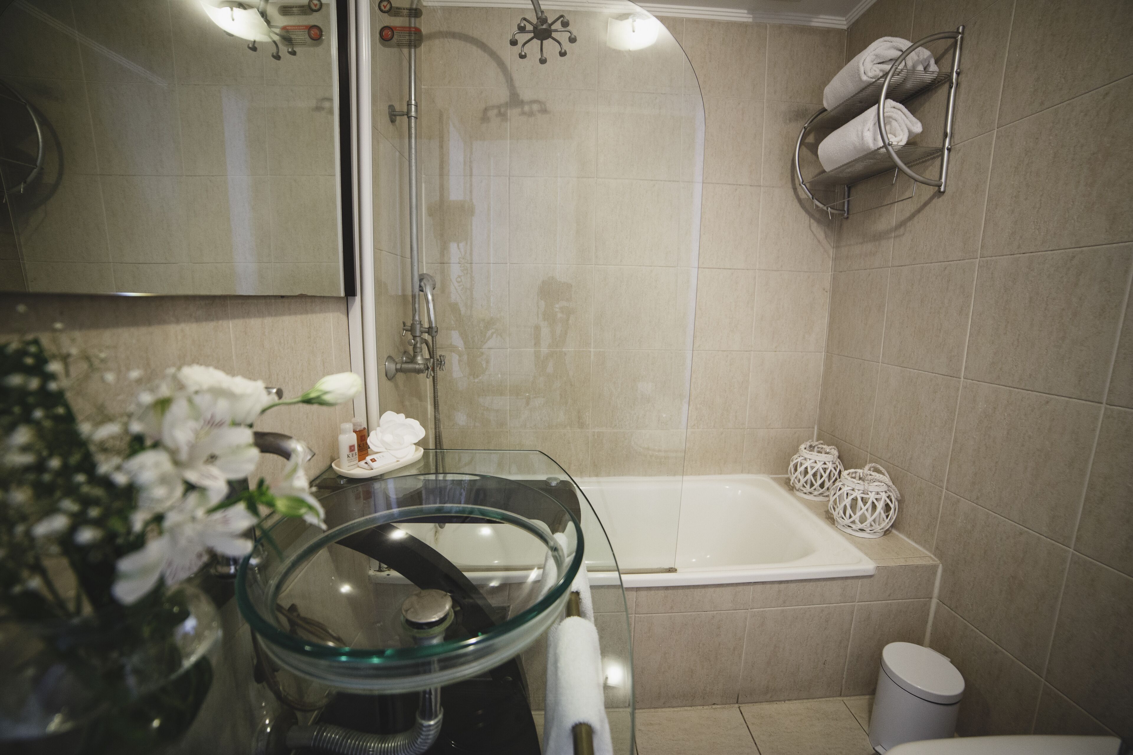 Une salle de bain dotée d’une douche à parois de verre, d’une baignoire, de toilettes et d’un lavabo avec un récipient en verre.