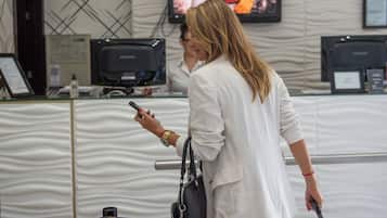 Una persona de pie frente a una mesa de recepción con un monitor de computadora, un televisor montado en la pared y un diseño de pared con motivos.