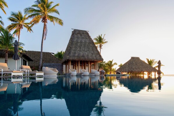 Una piscina al aire libre, sombrillas, sillones reclinables de piscina