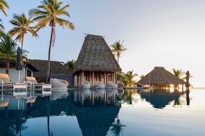 Una piscina al aire libre, sombrillas, sillones reclinables de piscina
