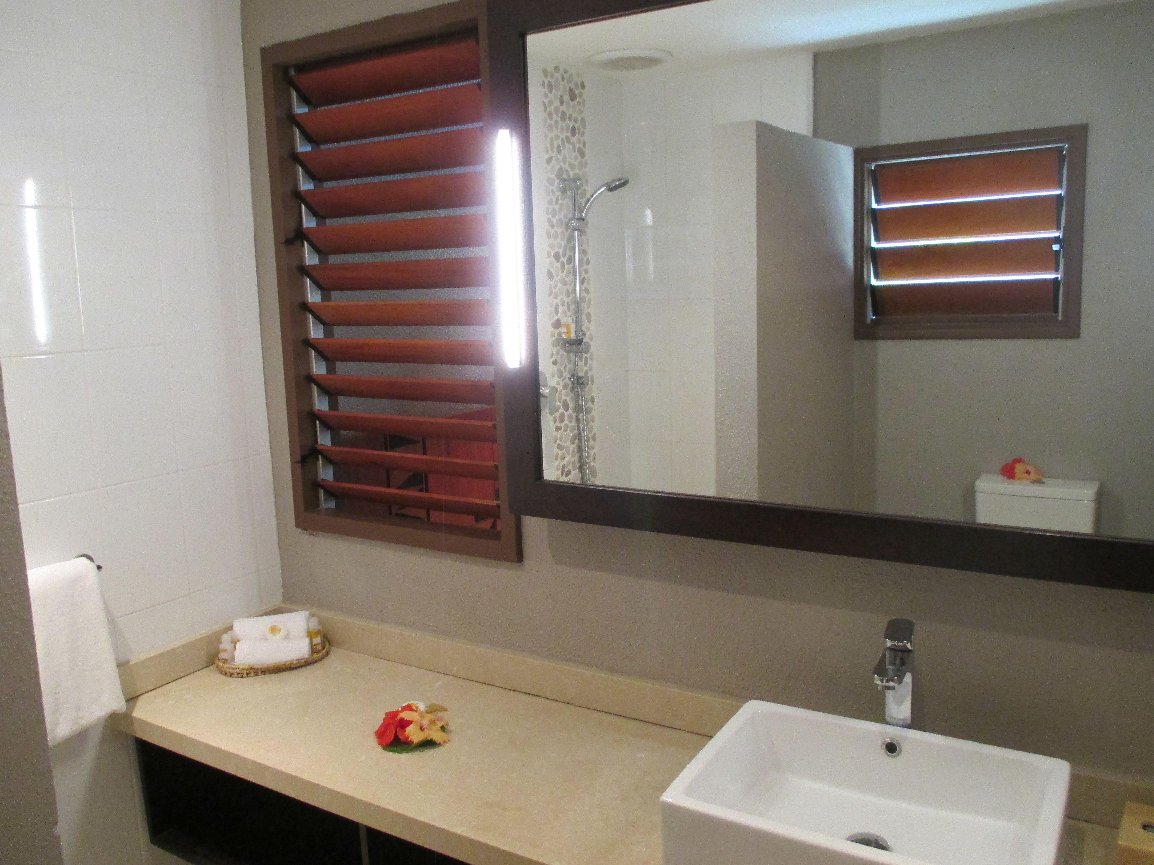Un baño con lavamanos blanco, un espejo y ducha.