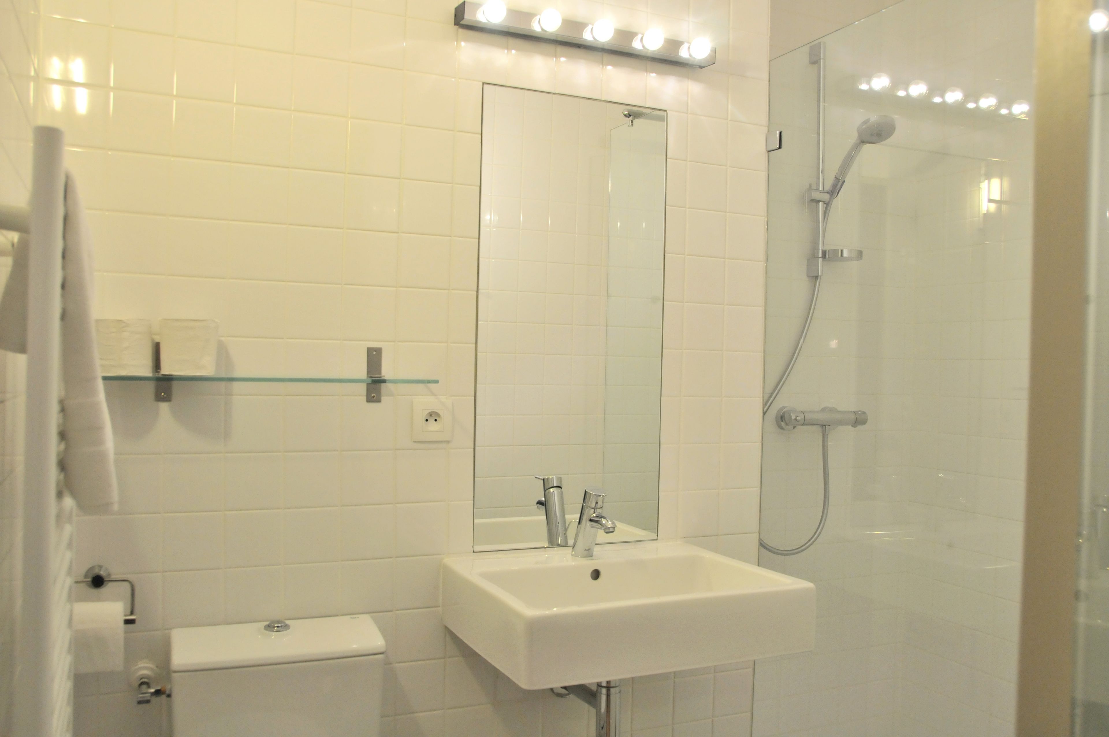 A bathroom with a white sink, mirror, and shower.