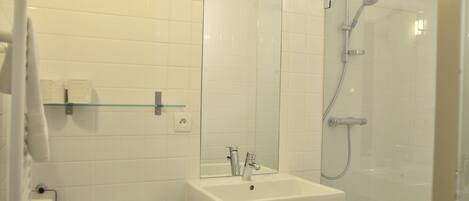 A bathroom with a white sink, mirror, and shower.