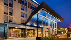 A modern hotel with a glass facade, large signage, and a well-lit entrance area. - Aloft by Marriott Milwaukee Downtown (Milwaukee)