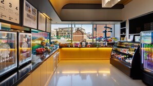 A modern Starbucks with a clean interior, a counter with various items, and a view of the cityscape. - Aloft by Marriott Milwaukee Downtown (Milwaukee)