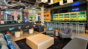 A modern bar area with a neon sign, a bar counter, and a seating area with sofas and chairs. - Aloft by Marriott Milwaukee Downtown (Milwaukee)