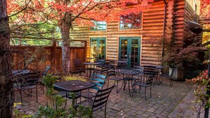 A log cabin with outdoor seating and a wooden deck. - The Lodge at Riverside (Grants Pass)