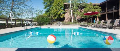 A swimming pool with lounge chairs and a lifeguard stand.