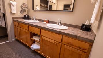 A bathroom with two sinks, wooden cabinets, a mirror, and a towel rack.
