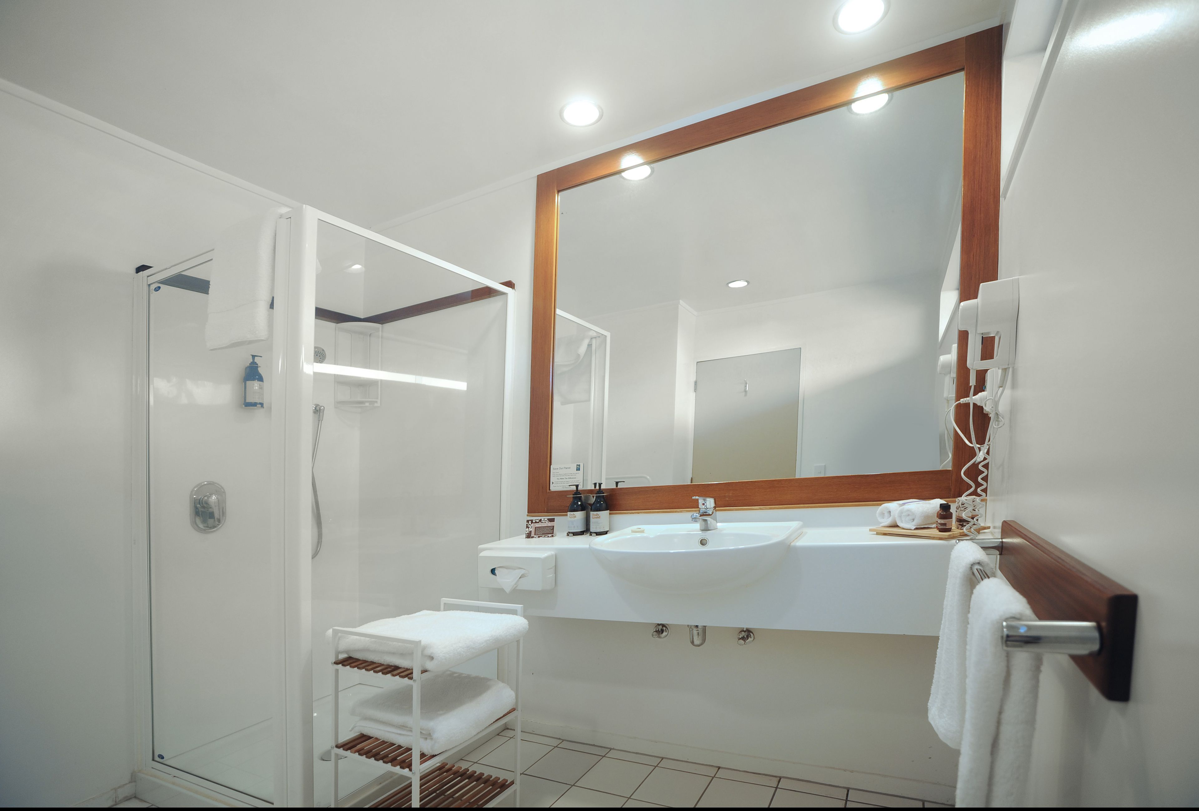 A modern bathroom with a glass-enclosed shower, a large mirror, and a white sink.