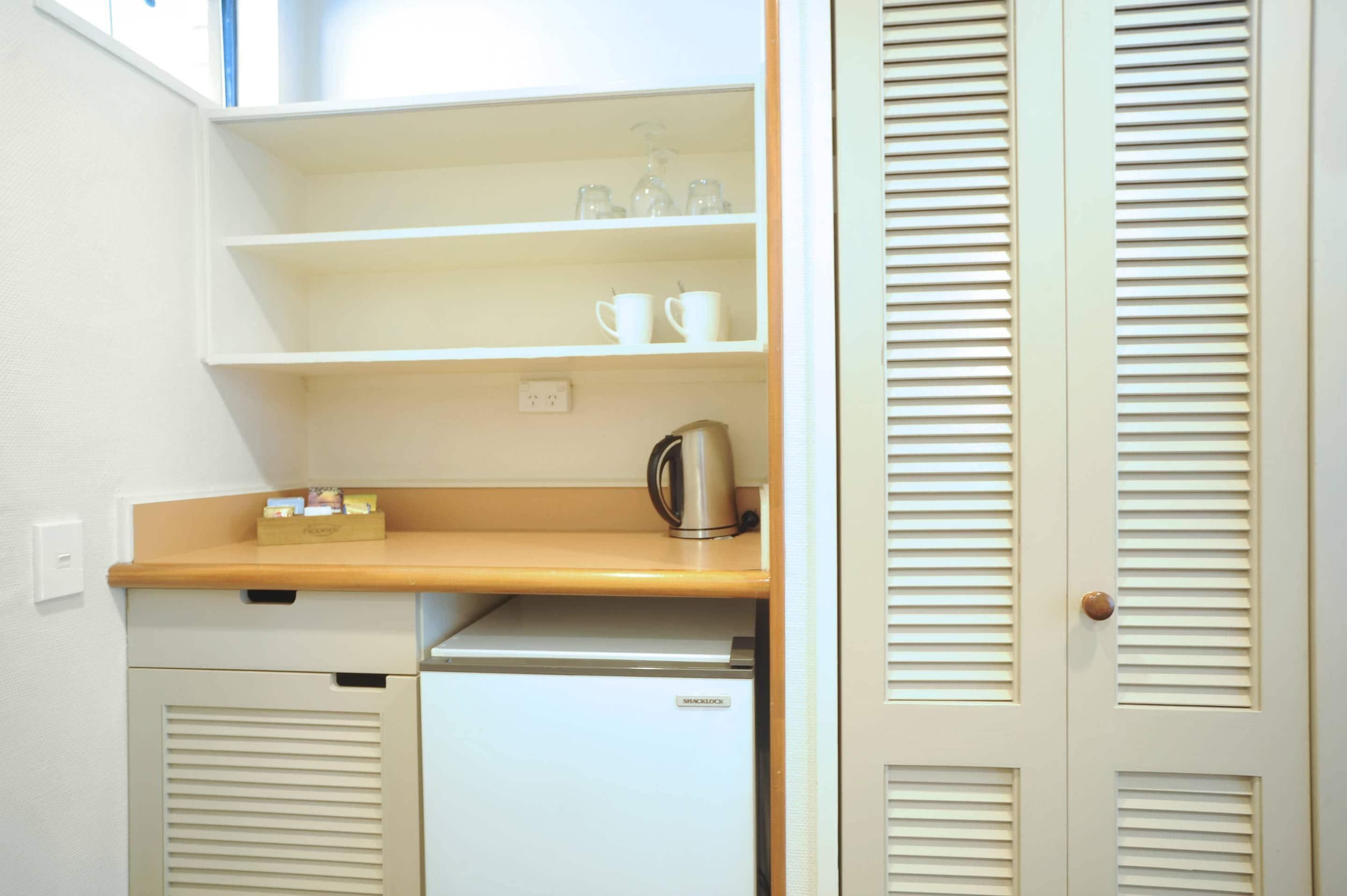 A compact kitchenette with a countertop, a coffee maker, and a mini-fridge.