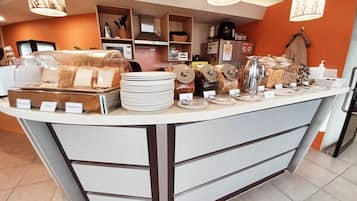 A buffet counter with various food items and utensils, including plates, bowls, and jars, with labels indicating different food options.
