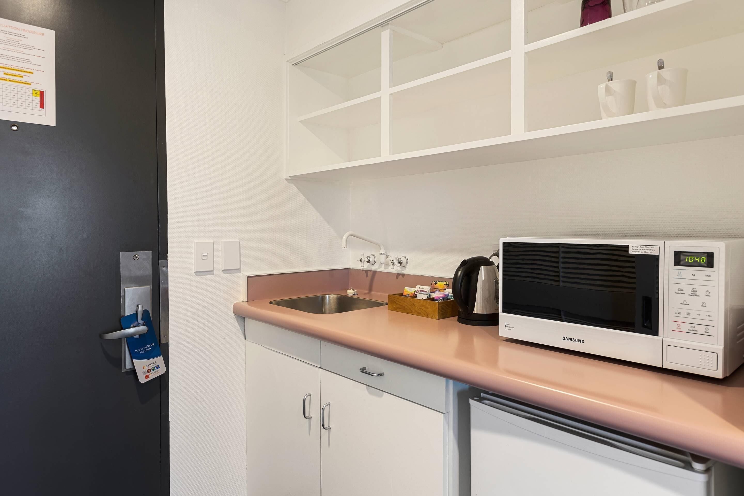 A kitchenette with a microwave, sink, and cabinets.