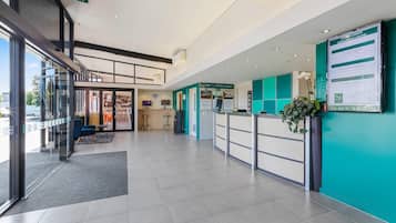 Een hotel receptiegebied met een glazen ingang, een receptiebalie, een zithoek en een bord met daarop 'conferentiecentrum'.