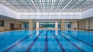 An indoor swimming pool with clear lane markings, a high ceiling with a geometric pattern, and a view of the outside through large windows. - The Westin Tianjin (Tianjin)