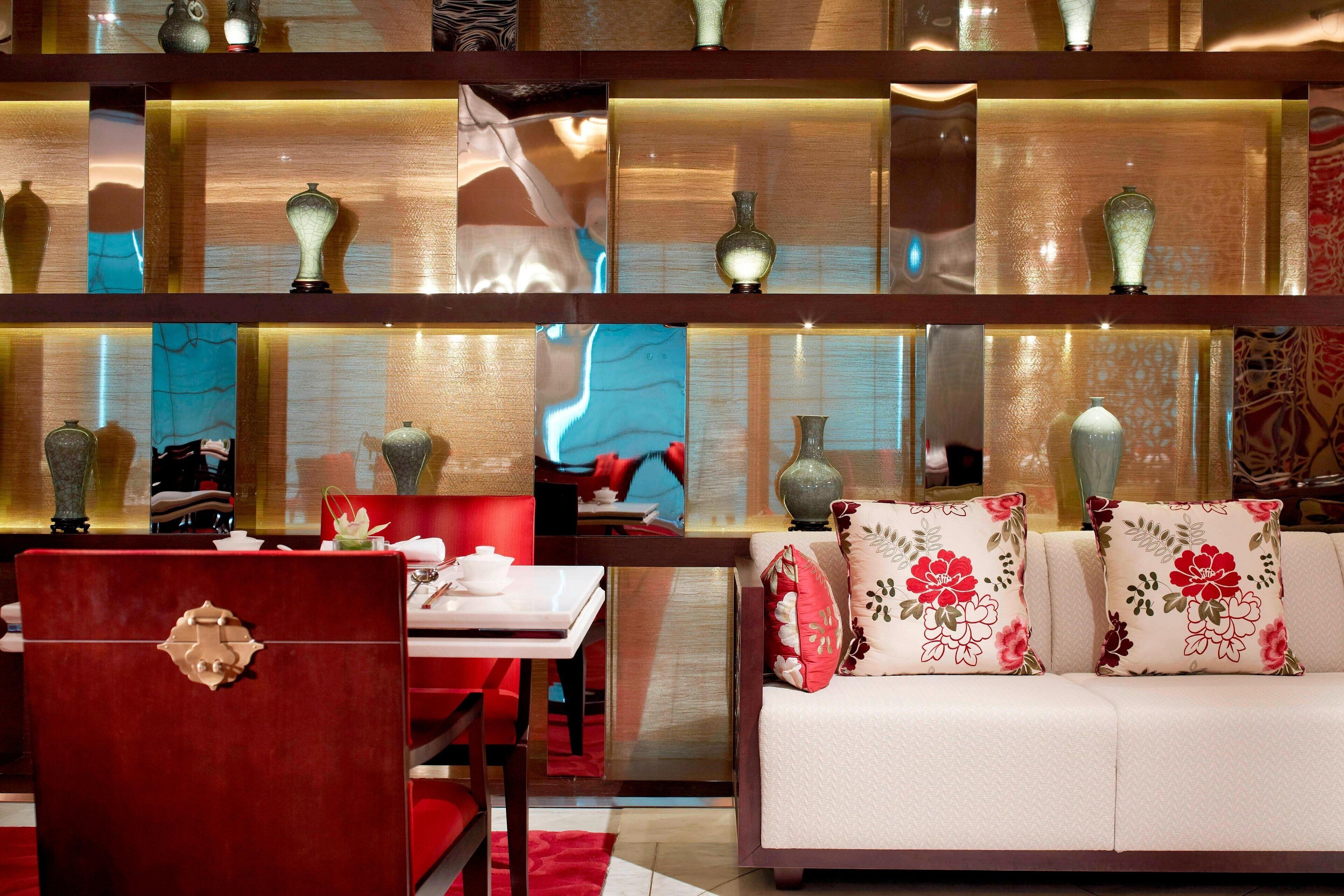 A modern interior with a sofa, red armchair, and a table with a vase.