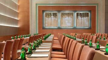 A conference room with rows of chairs and tables, each with a nameplate and a green bottle.