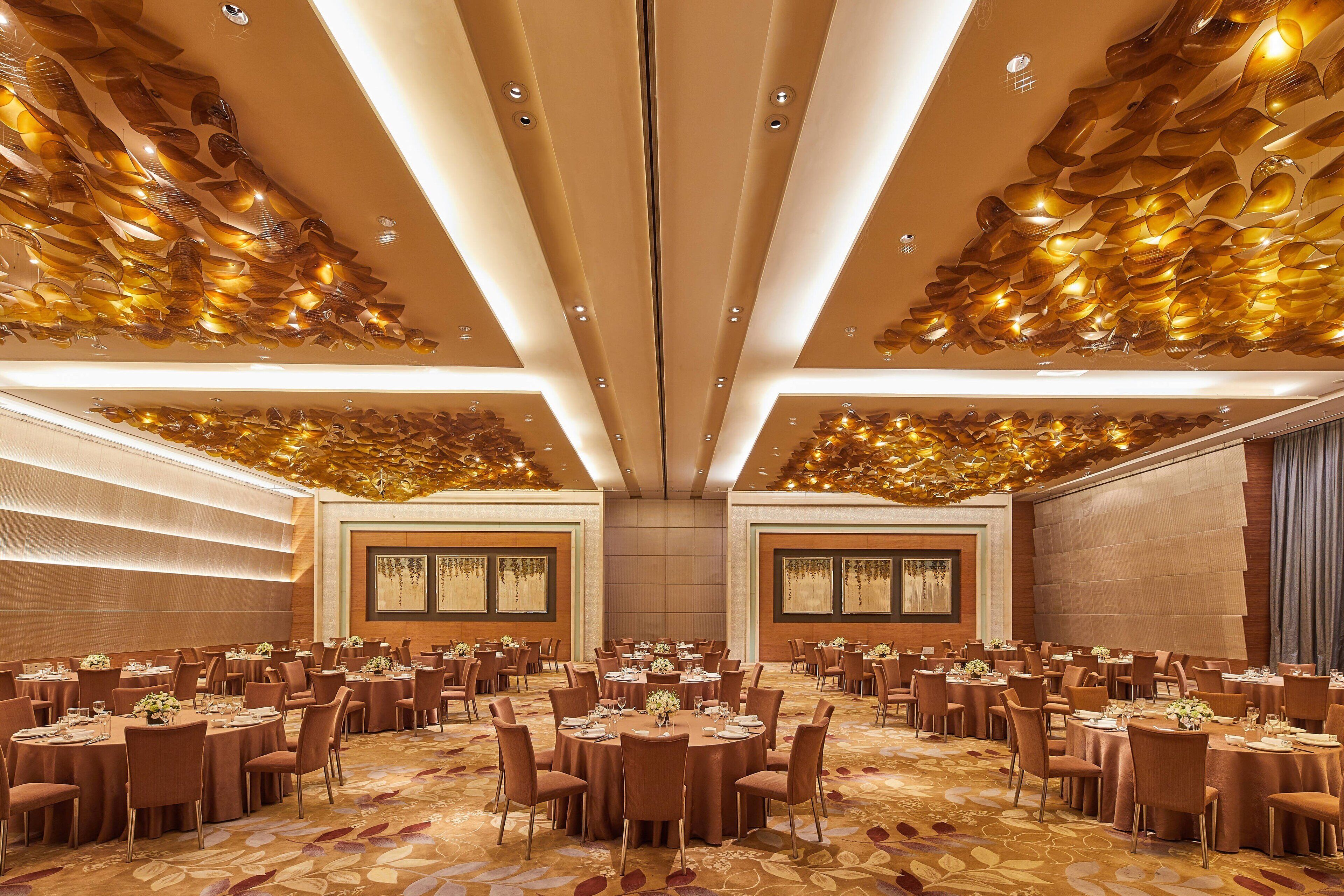 A large banquet hall with round tables, chairs, and a decorative ceiling.