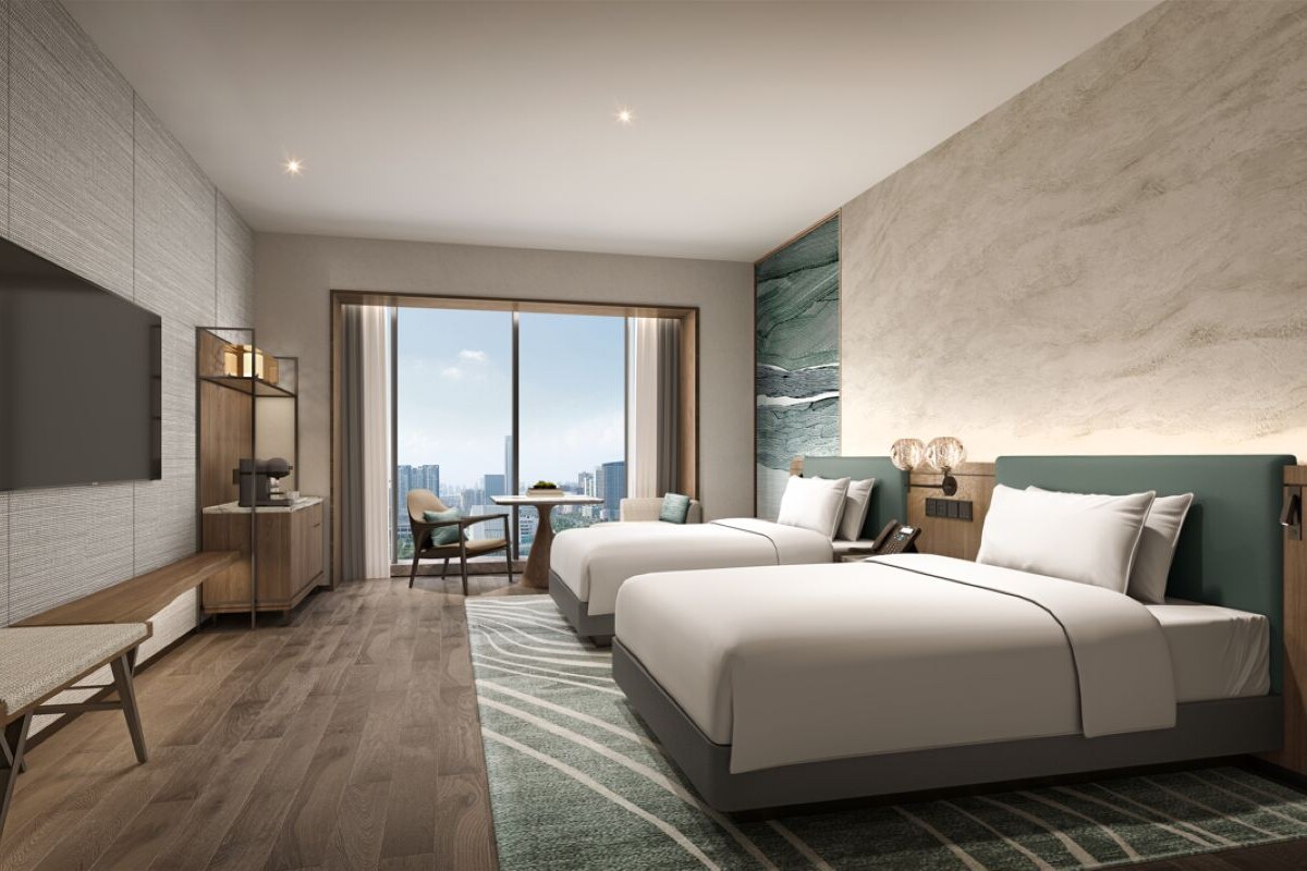 Una habitación de hotel moderna con una cama grande, un escritorio, una silla y un televisor en la pared.