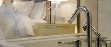 Un baño moderno con un grifo cromado, un espejo y una mesita de noche con una lámpara.