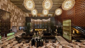 A spacious lobby with a checkered floor, a reception desk, seating areas, and a decorative wall with a geometric pattern. - The Westin Tianjin (Tianjin)