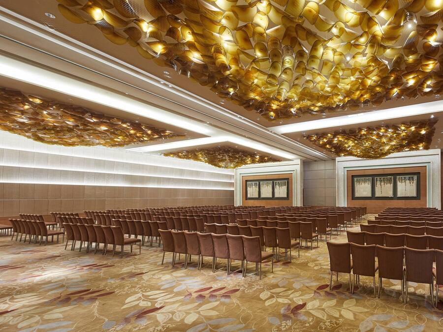 A conference room with rows of chairs, a patterned carpet, and a ceiling with a unique light fixture.