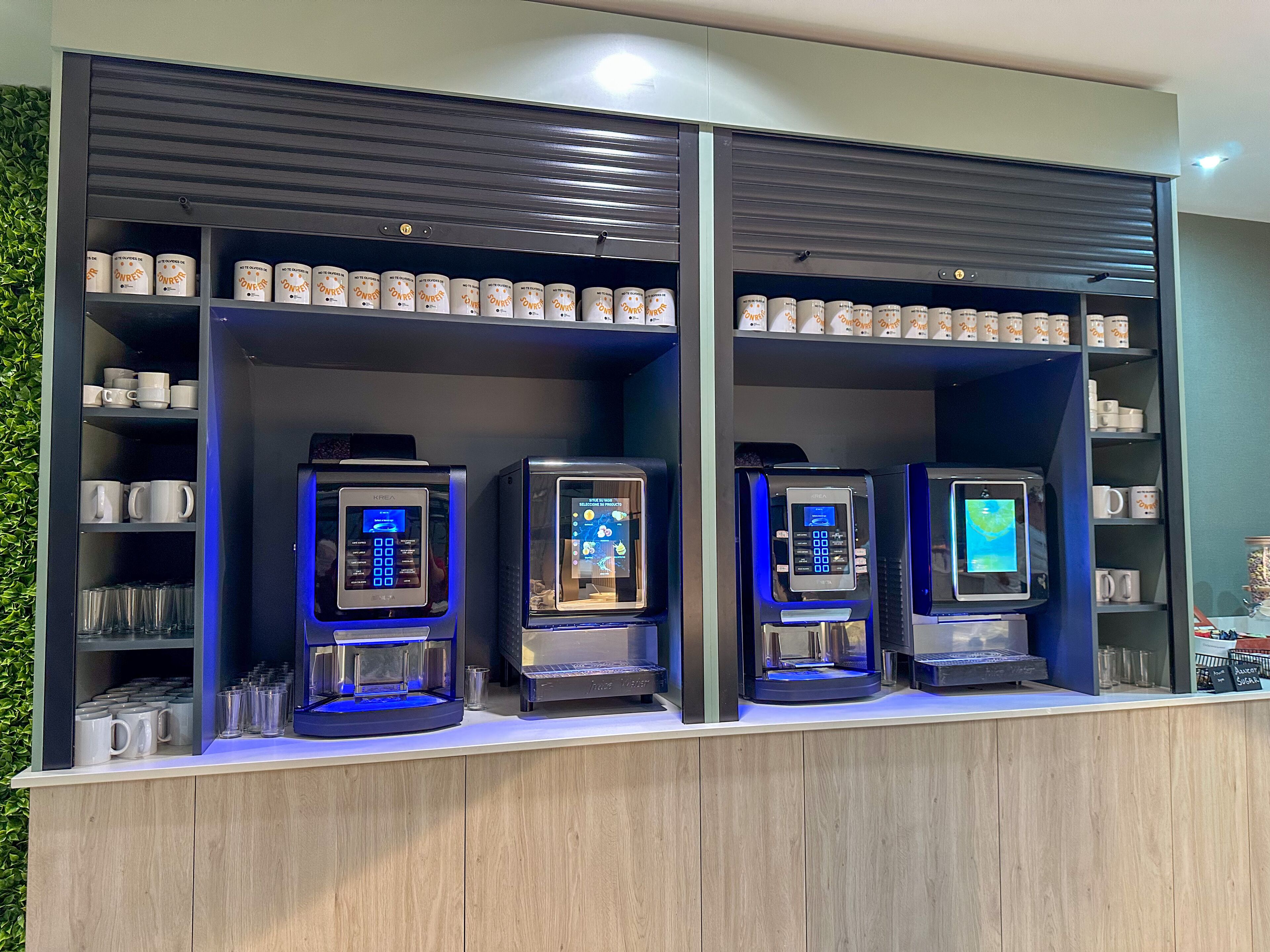 Una estación de café con tres máquinas de café y una exhibición de cápsulas.