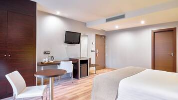 A hotel room with a bed, a desk with a chair, a television, and a coffee machine.