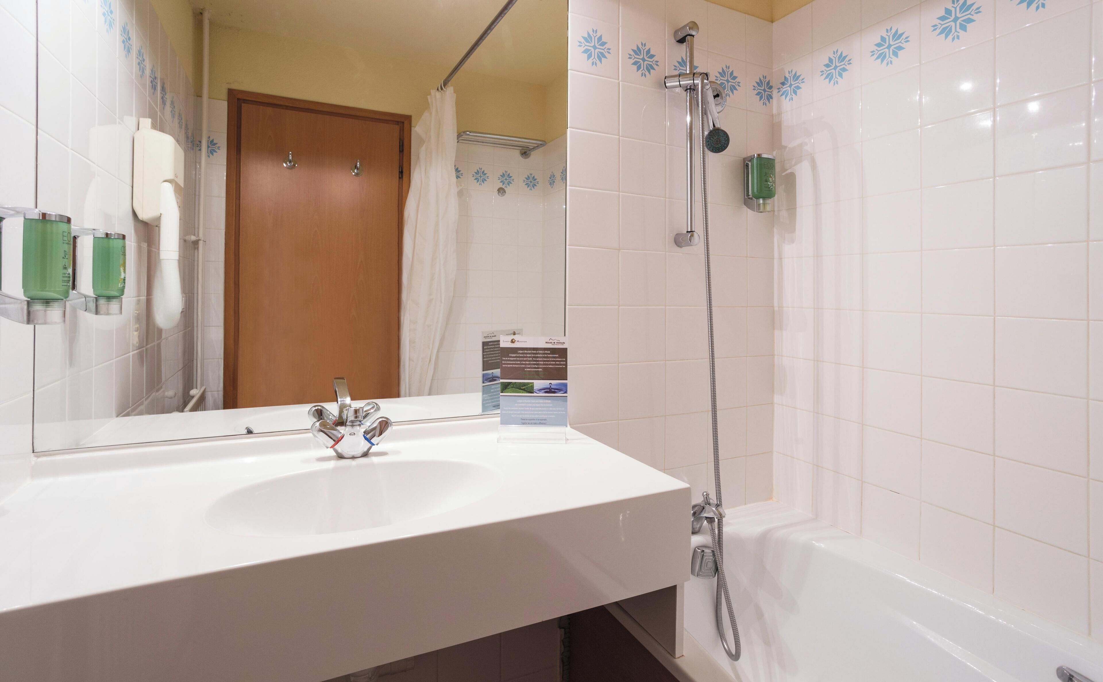 A bathroom with a white sink, a shower with a handheld showerhead, and a mirror.